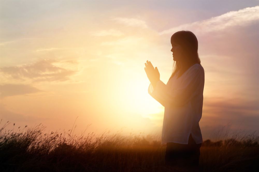 woman praying in the sunlight