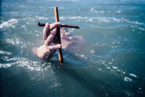 person under water holding cross above the water with hand