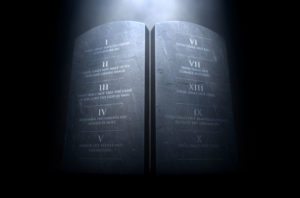 A 3D render of two stone tablets with the ten commandments etched on them lit by a dramatic spotlight on a dark background