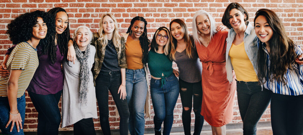 Cheerful diverse women standing in front of a red brick wall