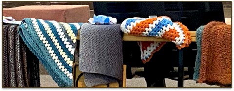 different crochet and knitted shawls laid out on a table