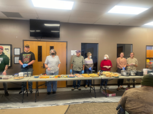 Volunteers from Heart of Longmont stand behind a row of tables set to serve clients at HOPE supper