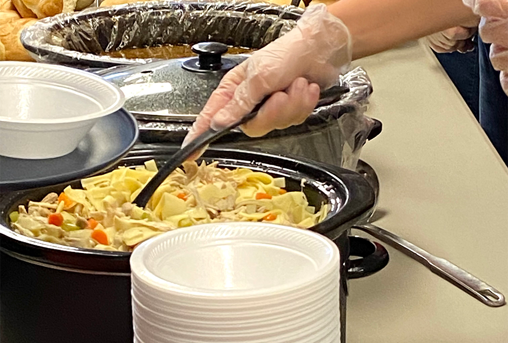 Someone serving chicken noodle soup at HOPE