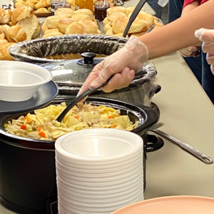 Someone serving chicken noodle soup at HOPE