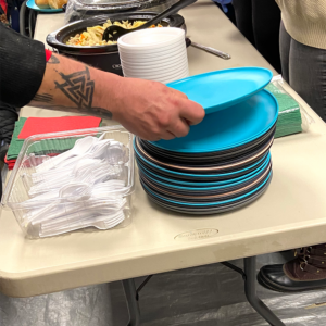 Someone taking a blue plate from a stack of multicolored plates at HOPE