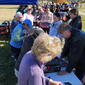 A photo from the November 2023 gun safe giveaway. Volunteers stand at tables while a long line of people wait to speak to them.